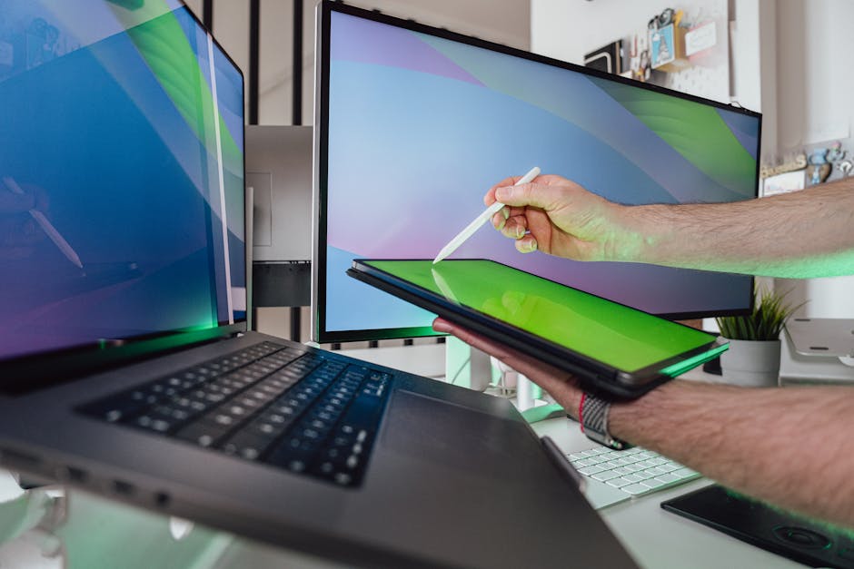 A person using a stylus on a tablet in a tech-savvy workspace with dual monitors.