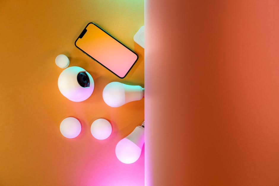 Top view of smart home gadgets including smartphone, camera, and light bulbs in a colorful setup.